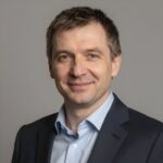 Портрет уверенного российского бизнесмена с дружелюбным взглядом на размытом нейтральном фоне в студии