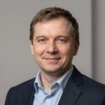 Портрет уверенного российского бизнесмена с дружелюбным взглядом на размытом нейтральном фоне в студии