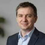 Портрет уверенного российского бизнесмена с дружелюбным взглядом на нейтральном размытом фоне студии